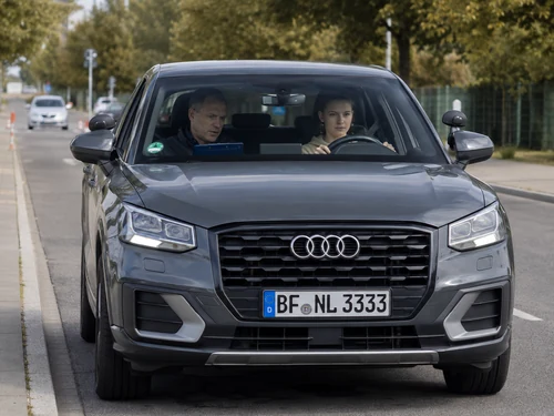 Grauer Audi Q2 mit Kennzeichen BF NL 3333 bei einer Fahrsituation mit Fahrerin und prüfender Begleitperson.